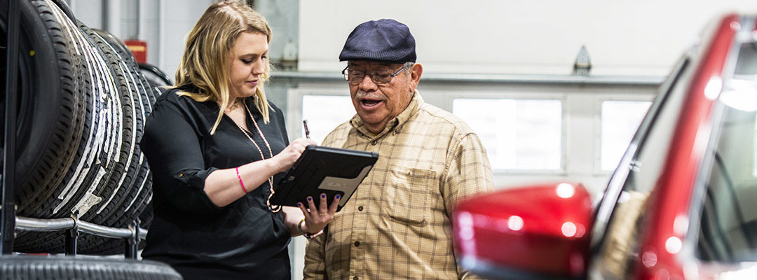 man in a hat looking at service employee's tablet